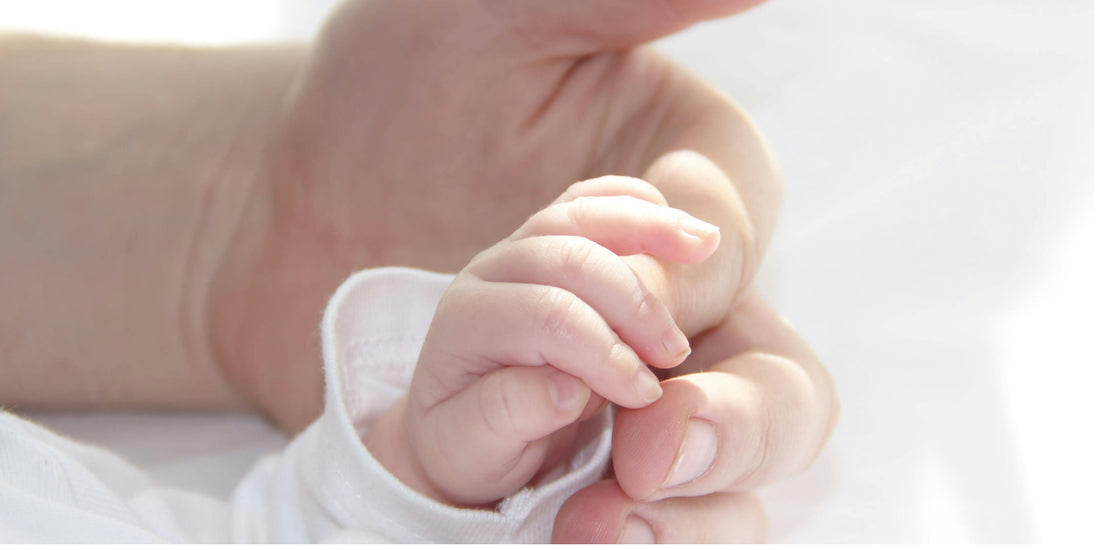 Close-up of a newborn baby gently holding a parent’s finger, showing a calm and intimate moment of early bonding.