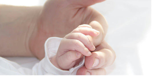 Close-up of a newborn baby gently holding a parent’s finger, showing a calm and intimate moment of early bonding.